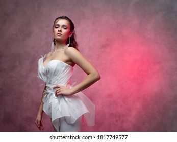 Portrait Of A Young Beautiful Woman In A Smart White Pantsuit, Textured Pink Background. Bride In A Modern Style