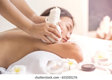 portrait of young beautiful woman in spa environment, massage with spa herbal balls