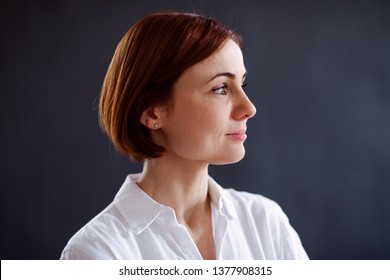 A portrait of young beautiful woman standing against dark background.