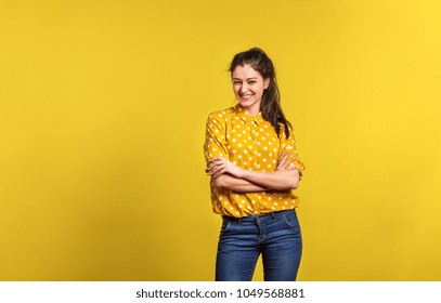 Portrait Of A Young Beautiful Woman In Studio On Yellow Background.