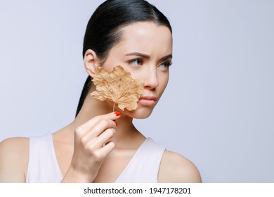 Portrait Of Young Beautiful Woman Suffering The Dryness On Skin, Holds Dry Leaf.