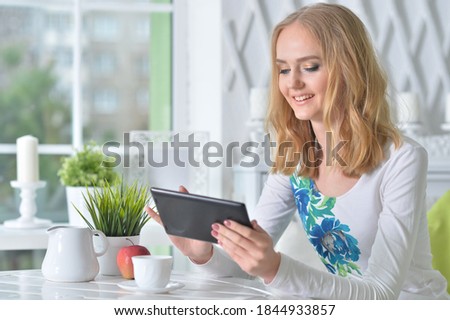 Portrait of young beautiful woman with tablet sitting at table
