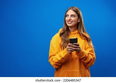 Portrait of young beautiful woman texting on the phone against blue background - Shutterstock ID 2206485347