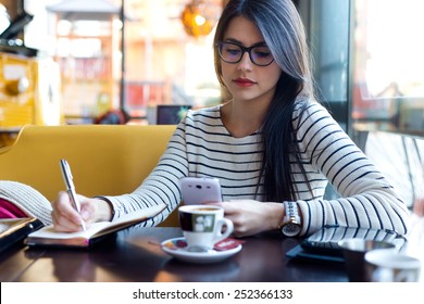 Portrait of young beautiful woman using her mobile phone in coffee. - Powered by Shutterstock