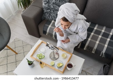 Portrait Of A Young Beautiful Woman Wearing A Bathrobe At Home. Doing Her Daily Skincare Routine With  Natural Cosmetics 