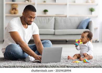 Portrait Of Young Black Father Using Laptop And Taking Care Of His Baby At Home, Millennial Freelancer Man Working Remotely On Computer With Adorable Infant Child Sitting Next To Him, Free Space