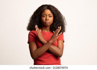 Portrait Of Young Black Female Showing Stop Gesture With Crossed Hands, Serious Millennial African American Woman Refusing Something While Posing Over White Studio Background, Copy Space