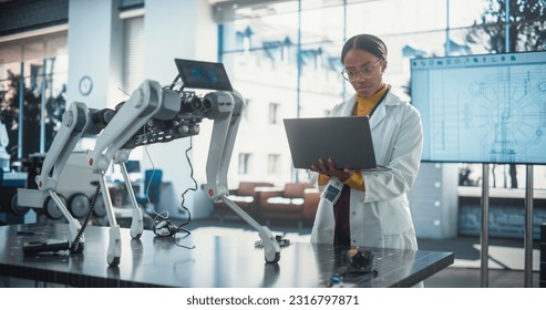 Portrait of Young Black Female Specialist in Lab Coat Using Laptop to Test an AI Robotic Prototype. Professional, Successful Woman Working as an Engineer in Modern High Technology Company Startup - Powered by Shutterstock