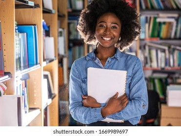 Portrait Of Young Black Female Student .She Standing In College Library.