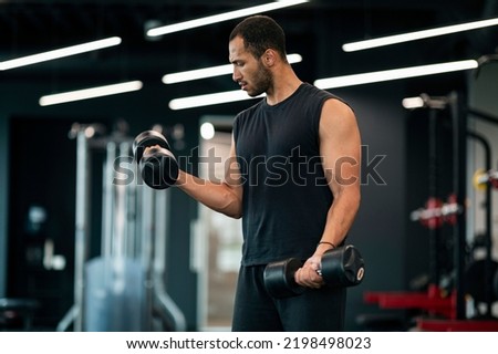 Portrait Of Young Black Male Athlete Exercising With Dumbbells At Fitness Club, Muscular African American Man Using Heavy Sport Equipment For Biceps Workout At Gym, Enjoying Bodybuilding