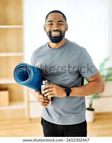 Portrait of a young black man posing with mat in sportswear prepering to exercise at home gym