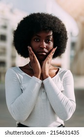 Portrait Of A Young Black Woman With Afro Hair Gesturing With Her Hands In A V Shape. Vertical