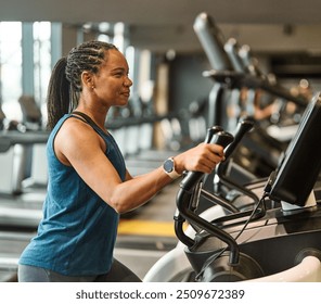 Portrait of a young black woman exercising on an elliptical trainer in a gym, running using  thereadmill machine equipment, healthy lifestyle and cardio exercise at fitness club concepts - Powered by Shutterstock