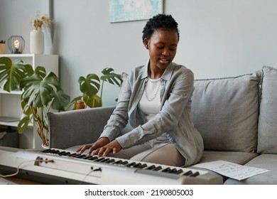 Portrait Of Young Black Woman Playing Synthesizer At Home And Composing Music In Cozy Home Setting, Copy Space