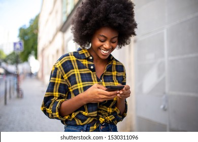 Portrait Of Young Black Woman Walking On Street And Looking At Mobile Phone