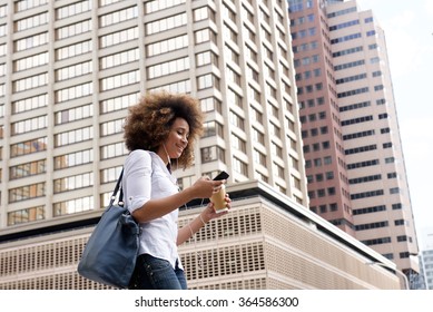 Portrait Of Young Black Woman Walking And Listening To Music On City Street