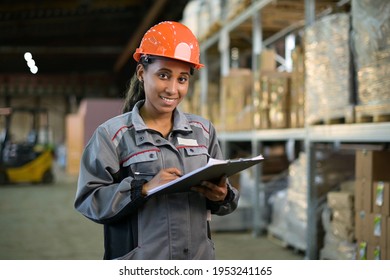 Portrait of a young black woman at work. Worker of production and warehouse in overalls and orange helmet - Shutterstock ID 1953241165