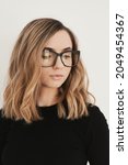 Portrait of a young blond woman with long bob haircut wearing eyeglasses with black frame. Eyewear. Vision and Eye care concept