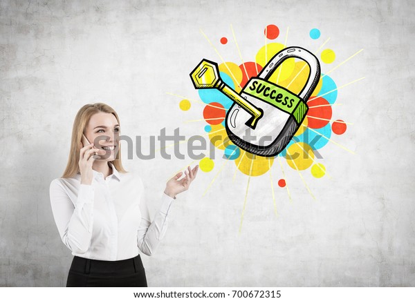 Portrait of a young blonde businesswoman\
wearing a white shirt and talking on a cell phone and\
gesticulating. Concrete wall with a key to success\
sketch