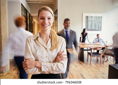 Portrait Of Young Blonde Woman In A Busy Modern Workplace
