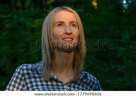 Portrait of a young blonde woman in the forest on which the rays of the sun fall