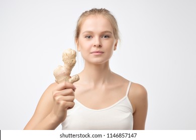 Portrait of young blonde woman holding raw ginger root. Healthy food for weight loss - Powered by Shutterstock