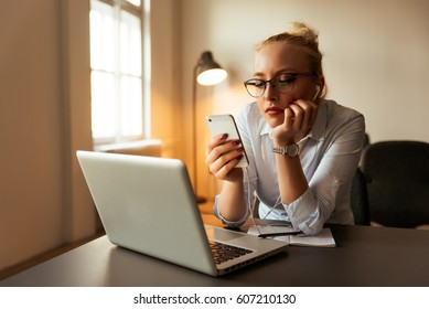 Portrait Of Young Bored Attractive Woman At Office Desk, With Laptop, Looking For Some Good Music