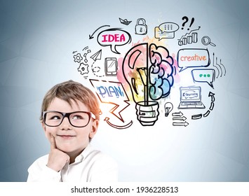 Portrait Of Young Boy In Glasses Looking Up And Dreaming About Future Opportunities. Colorful Lightbulb And Brain Sketch On Light Blue Wall. Concept Of Education, Success And Kids, Child Development