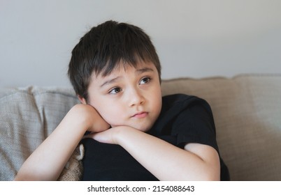 Portrait Young Boy Looking Deep In Thought, School Kid Looking Out With Thinking Face. Close Up Child With Curious Face Sitting Alone On Sofa.  