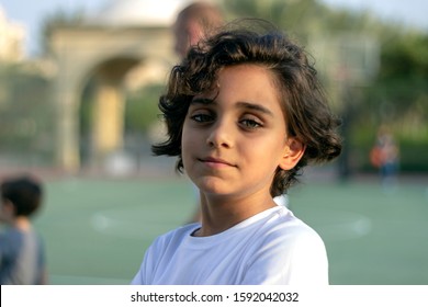 Portrait of young boy at outdoor basketball courtyard looking at camera.Close up shot of cute little boy standing on the basketball court and smiling.Handsome little basketball player with crossed arm