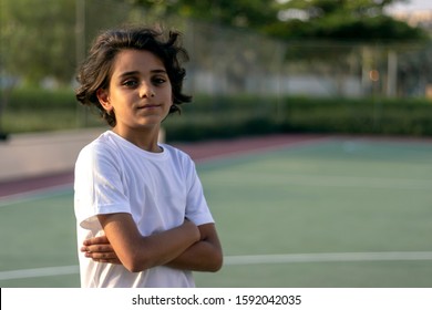 Portrait of young boy at outdoor basketball courtyard looking at camera.Close up shot of cute little boy standing on the basketball court and smiling.Handsome little basketball player with crossed arm
