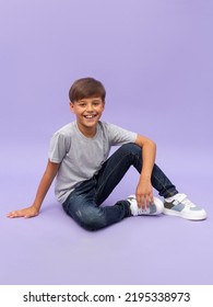 Portrait of young boy sitting isolated over a lilac background