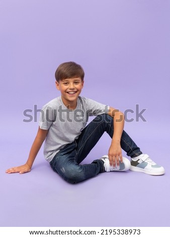 Portrait of young boy sitting isolated over a lilac background