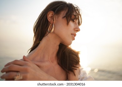Portrait of young brunette haired woman at the beach at sunset