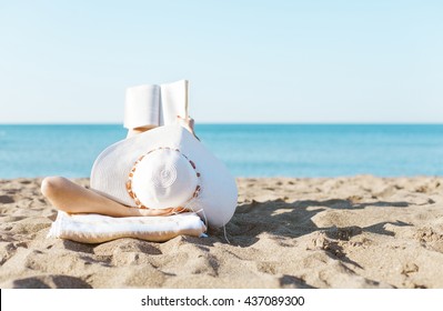 Portrait of a young brunette relaxing on the beach, reading a book