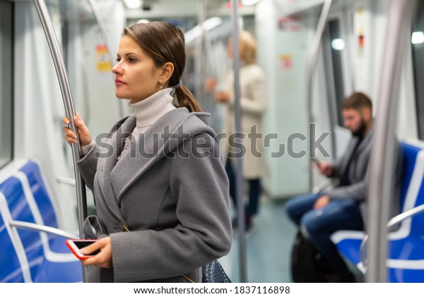 Portrait of young brunette traveling by subway car\
during daily commute to\
work..
