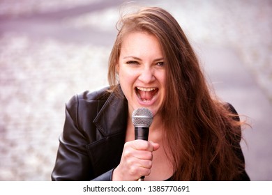 Portrait Of Young Brunette Woman Singing With Microphone Outdoors