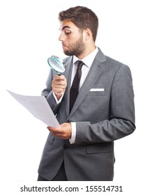 portrait of young business man looking a contract through a magnifying glass on white