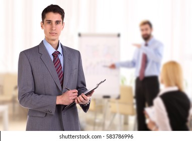 Portrait of young business man taking notes in office