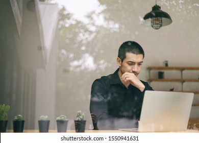 Portrait Of A Young Business Man Using Laptop Computer While Working. Young Asian Business Men Working With Laptop In Coffee Shop Cafe.