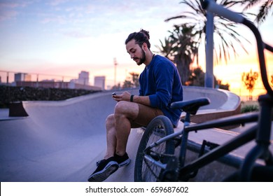 Portrait Of A Young Business Man Using Mobile Phone While Hanging Out In The Skate Park.