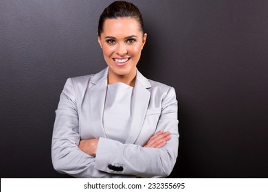 Portrait Of Young Business Woman With Arms Folded On Black Background