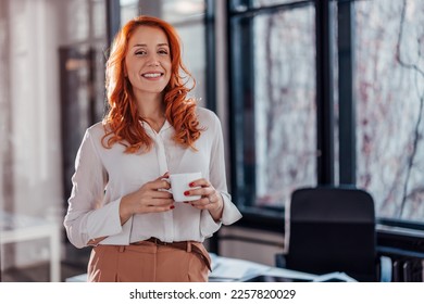 Portrait of a young business woman drinking coffee at the desk in the office. - Powered by Shutterstock