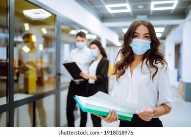 Portrait of young business woman in protective face mask an office building hallway. Office worker working during pandemic in quarantine city. COVID - 19. - Powered by Shutterstock