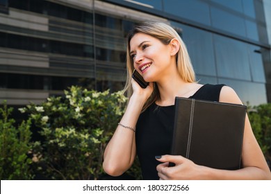 Portrait Of Young Business Woman Talking On The Phone While Standing Outdoors At The Street. Business Concept.