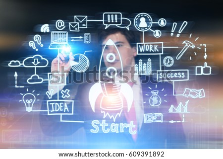 Portrait of a young businessman drawing a start up sketch on a glassboard. Blurred background.