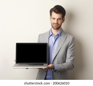 Portrait Of Young Businessman Holding Laptop In His Hand. Showing The Screen. Small Business.