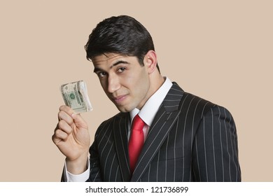 Portrait of a young businessman showing paper money over colored background