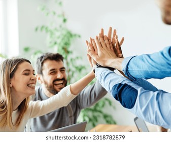 A portrait of young businesspeople celebrating with high five in the office - Powered by Shutterstock