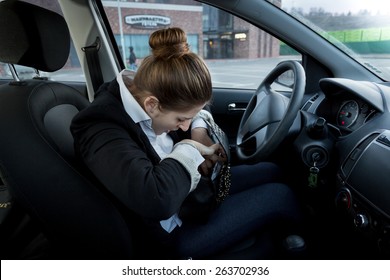 Portrait of young businesswoman sitting on drivers seat and looking inside handbag